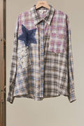 A long-sleeve plaid button-up shirt hanging on a wooden hanger, featuring a blue denim star patch and a lace applique pocket on the left side. The shirt has a beige, blue, and pink plaid pattern with brown buttons.