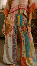 Woman wearing a colorful KANTHA quilt boho patterned outfit in a rustic indoor setting.