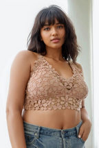 Woman wearing a beige lace top and blue jeans against a white background