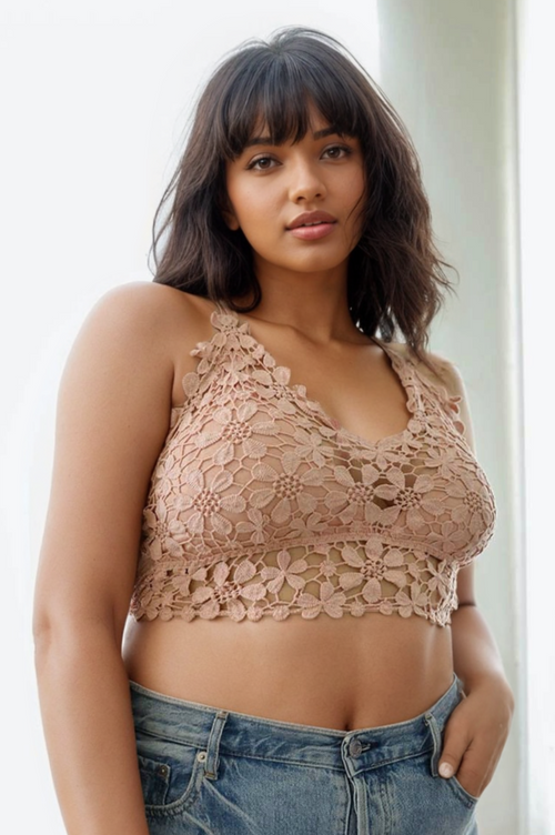 Woman wearing a beige lace top and blue jeans against a white background