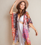Woman wearing a colorful floral kimono and white dress against a beige background