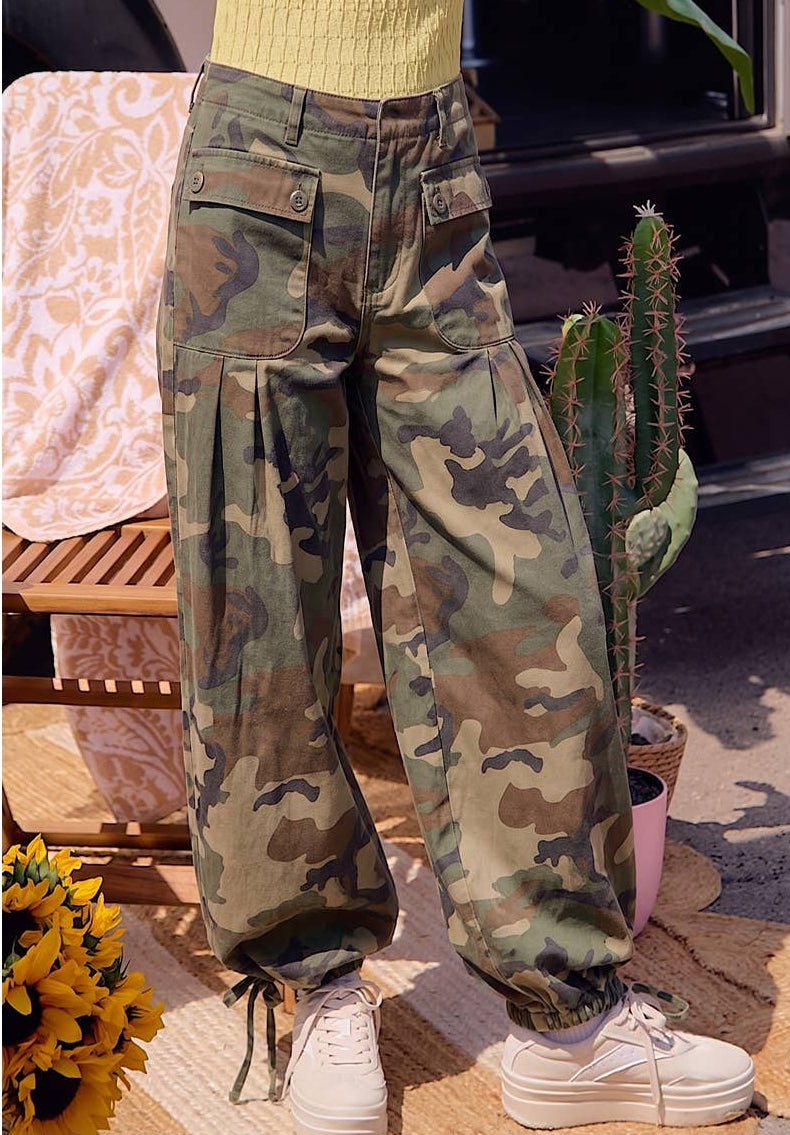 Person wearing camouflage pants with a cactus plant and outdoor furniture in the background